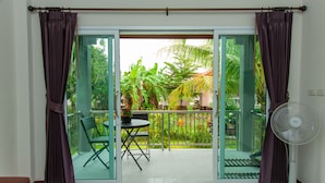 A room with a sliding glass door leading to a balcony with a table, chairs, and potted plants. - Cozy cottage with kitchen of Maenam 4 (Koh Samui)