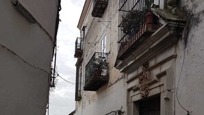 Une ruelle étroite pavée, bordée d’anciens bâtiments aux fenêtres grillagées et dotés de balcons.