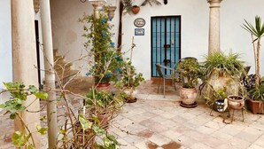 Une cour avec des plantes en pot, une porte bleue et un appareil de climatisation.