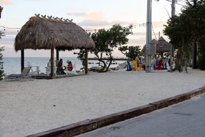 Une zone située au bord de la plage, avec des constructions à toits de chaume, une plage de sable et une vue sur la mer.