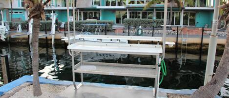 Un espace extérieur abrité avec un quai pour bateaux, des palmiers et un bâtiment aux couleurs bleu et blanc en arrière-plan.