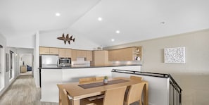 Una cucina moderna con isola centrale, tavolo da pranzo in legno e sedie.