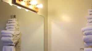 A bathroom with a sink, mirror, and towel rack. - Thunderbird Motel (Dodge City)