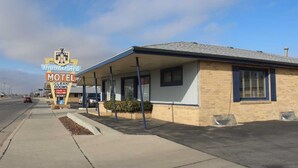 A motel with a covered parking area and a sign indicating clean rooms, color TV, cable TV, and a vacancy. - Thunderbird Motel (Dodge City)