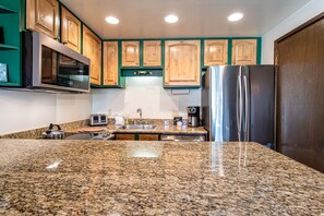 Una cocina con encimeras de granito, electrodomésticos de acero inoxidable, armarios de madera y una puerta de madera oscura.