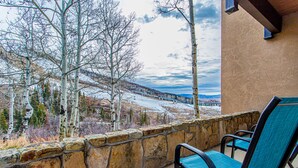 A stone wall with a chair and a view of a snowy landscape and a train. - Ski-In/Ski-Out Condo | Storm Meadows Club A! (Steamboat Springs)