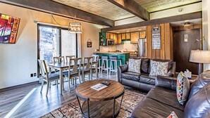 A modern living room with a leather sofa, a round coffee table, and a dining area with chairs and a table. - Ski-In/Ski-Out Condo | Storm Meadows Club A! (Steamboat Springs)