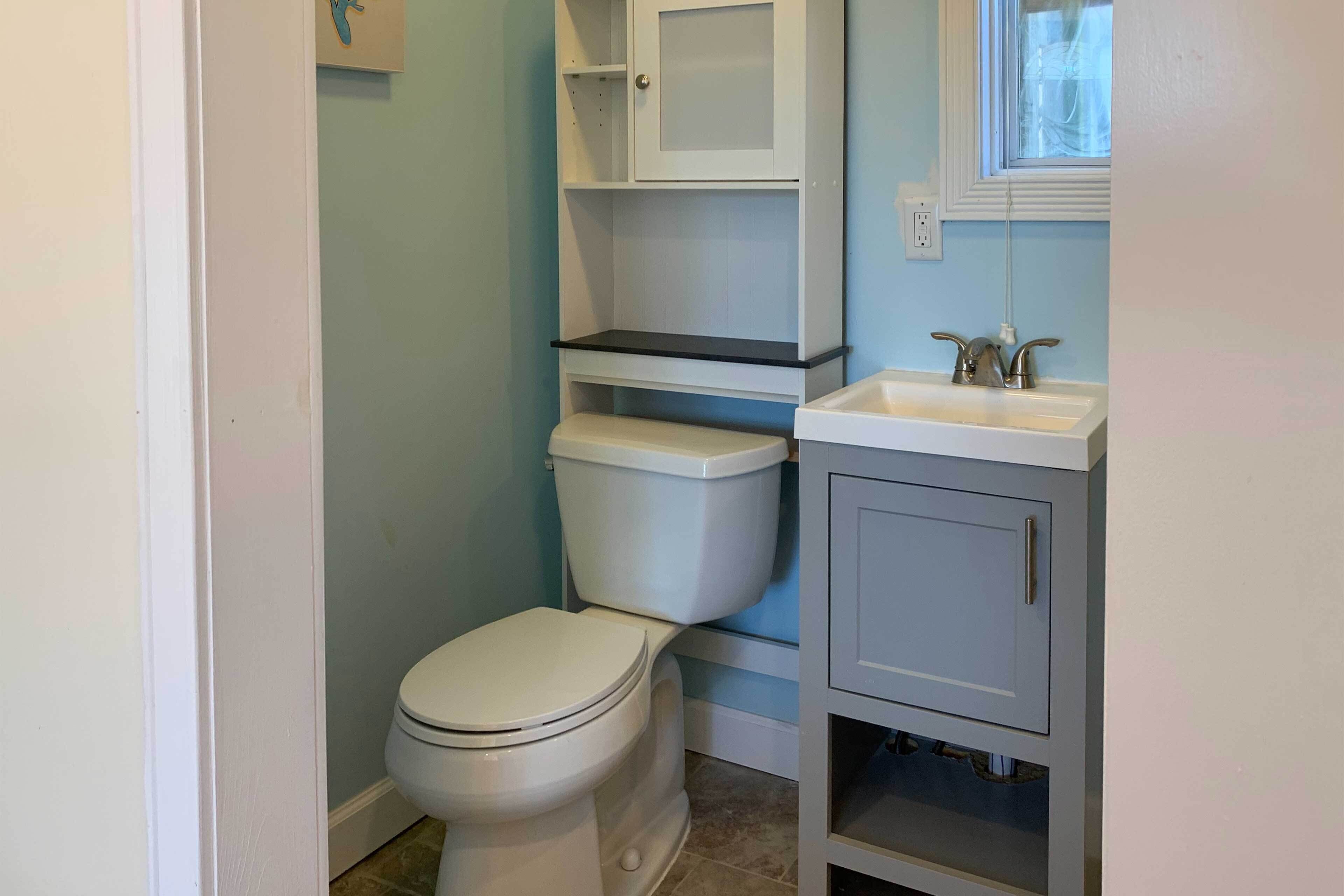 A bathroom with a toilet, a sink, and a cabinet.