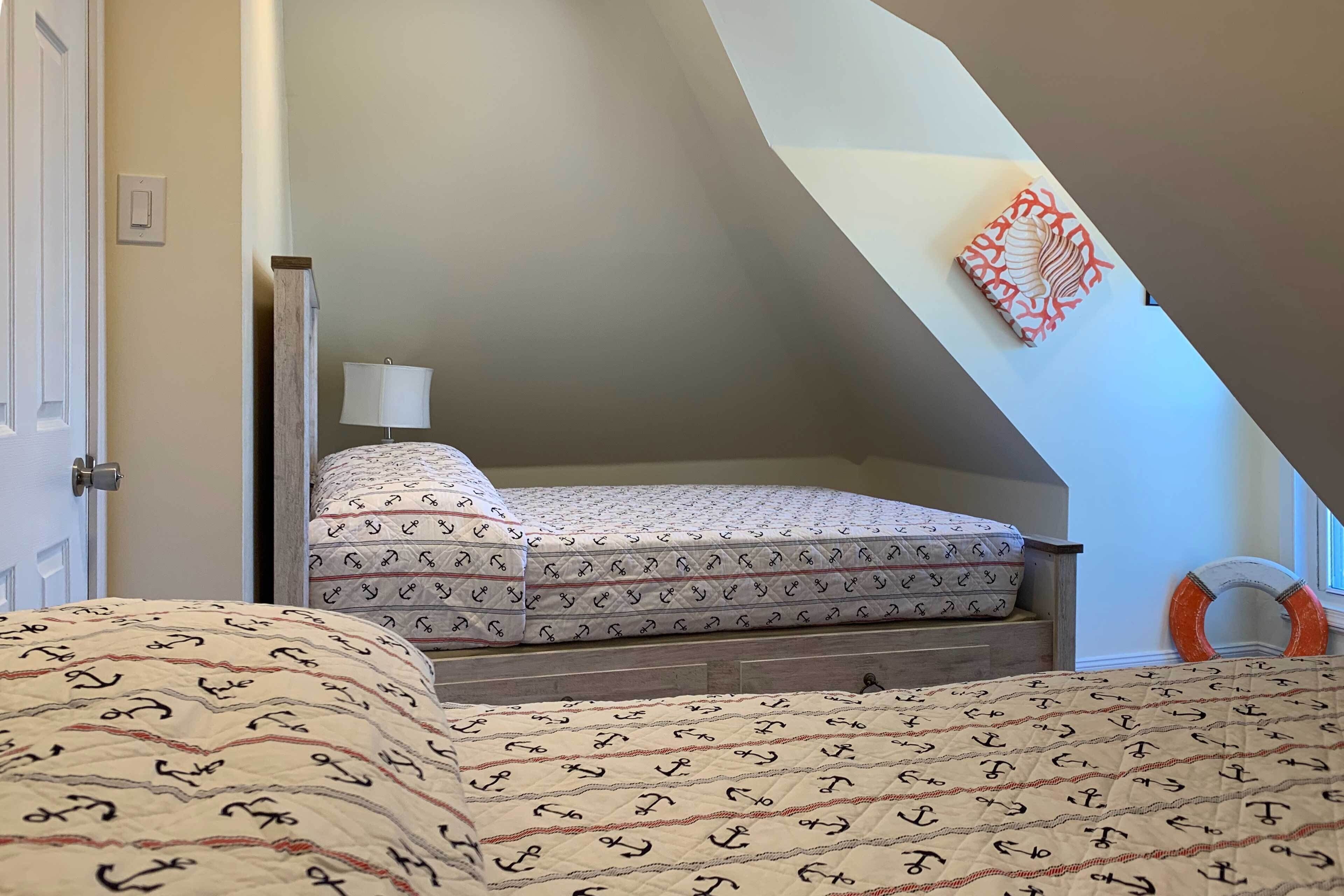 Een slaapkamer met een bed, nachtkastje, lamp en een kunstwerk aan de muur.