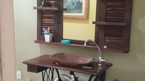 Une machine à coudre ancienne, avec un plateau en bois, un tableau encadré et une étagère contenant des articles de toilette.