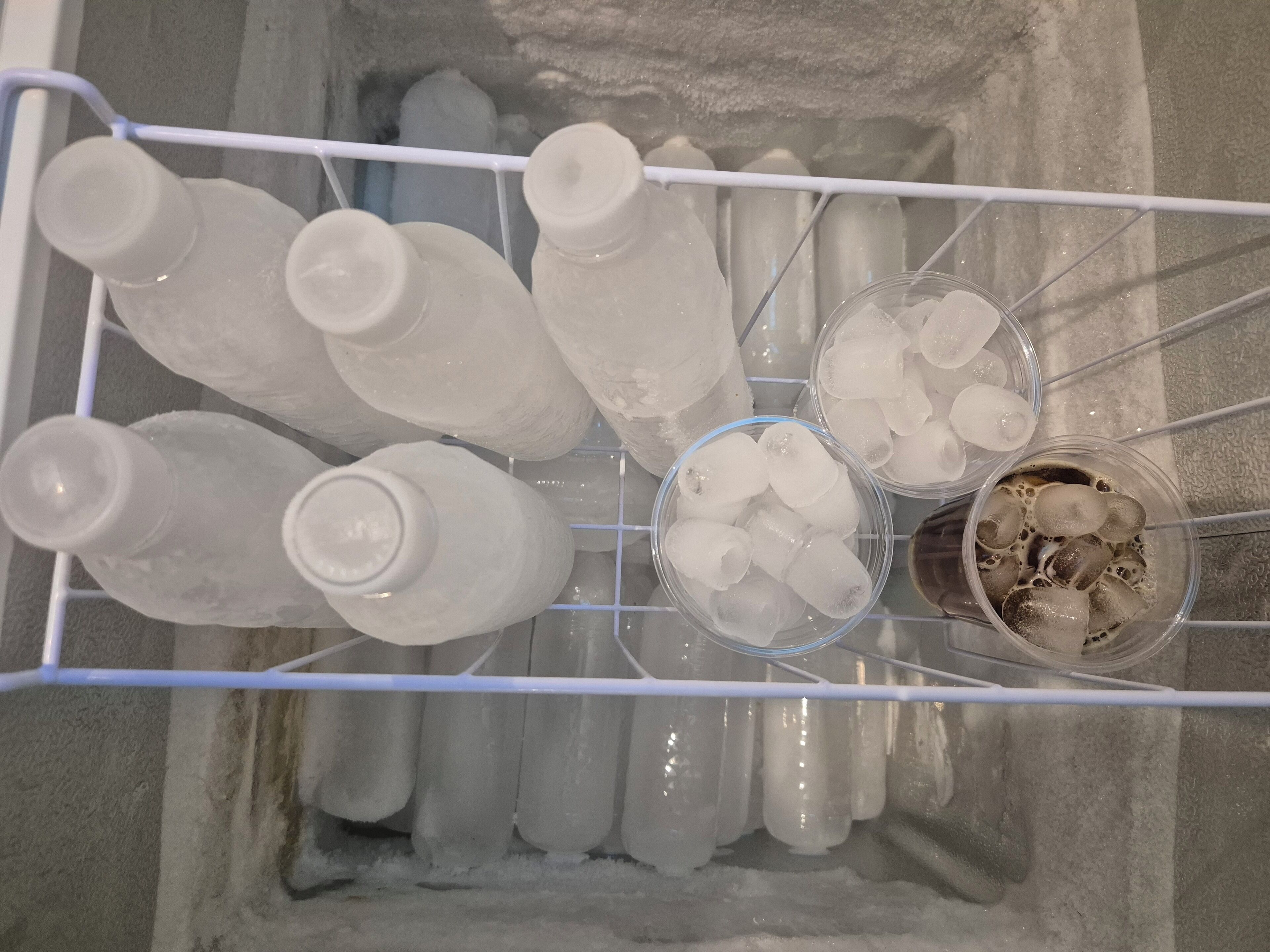 Un congelador con varias botellas y cubitos de hielo.