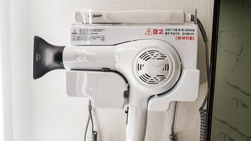 A hair dryer mounted on a wall with a cord.