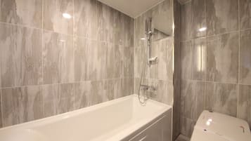 Un baño moderno con bañera, ducha e inodoro.