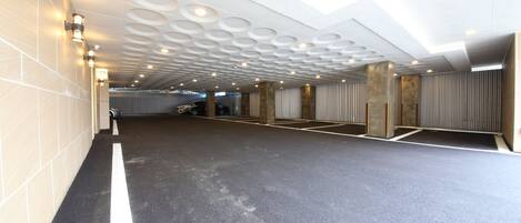 A spacious indoor parking area with a modern ceiling design featuring circular patterns and recessed lighting.