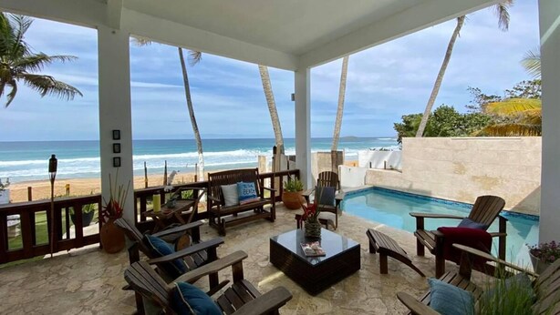 Ein überdachter Außenbereich mit Pool, mit Blick auf Strand und Meer.