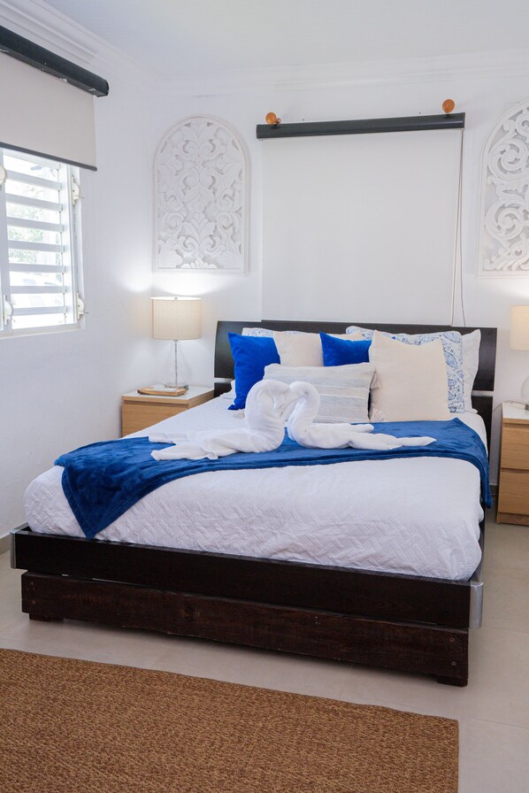 A neatly made bed with a blue and white bedspread, two nightstands with lamps, and decorative wall panels.