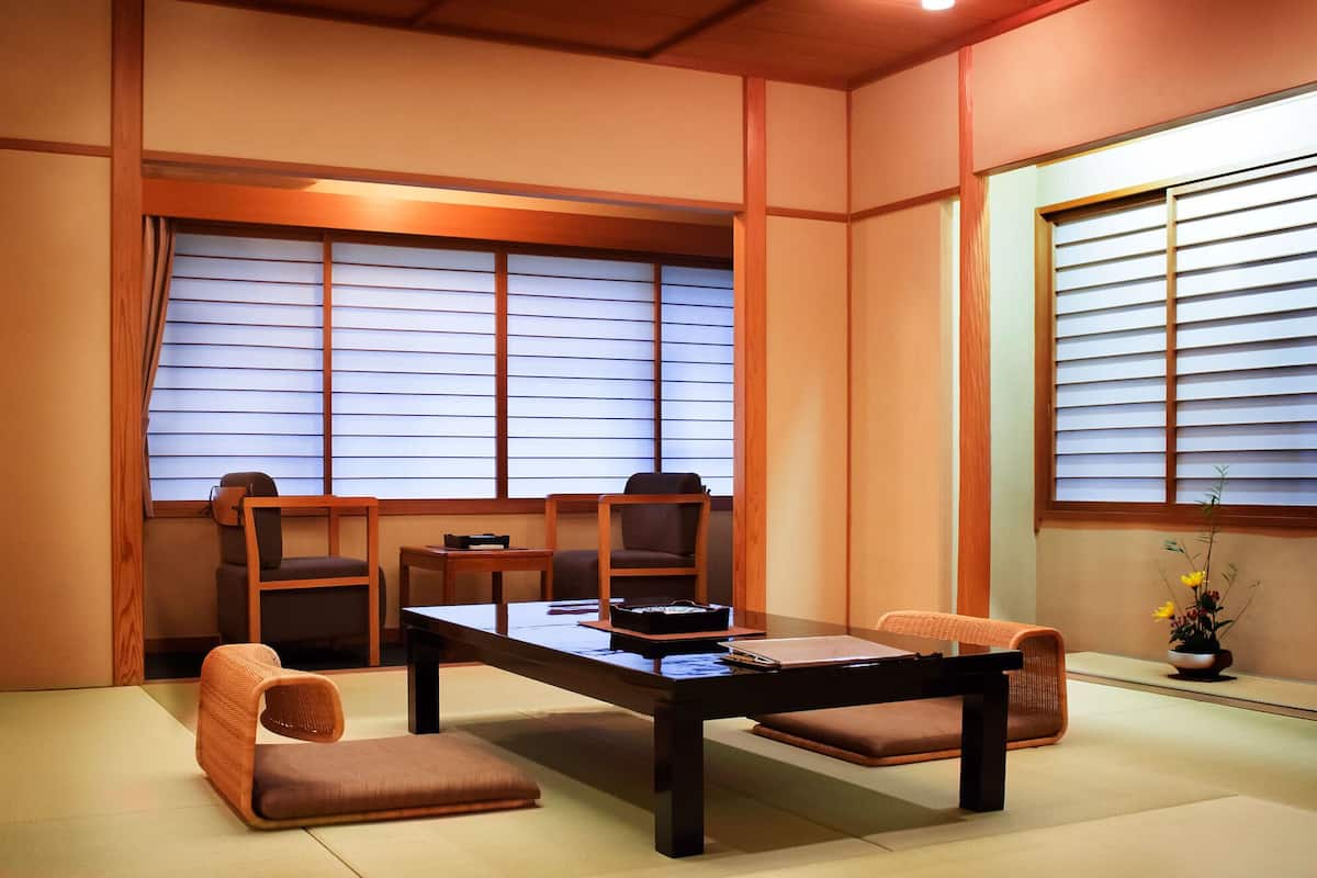 A traditional Japanese room with tatami flooring, a low table, and two chairs.