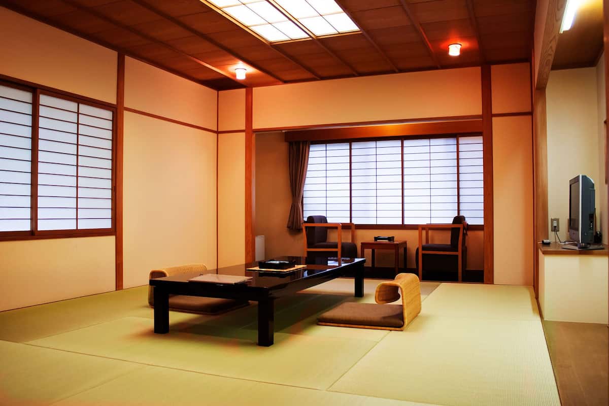 A traditional Japanese-style room with tatami flooring, a low table, chairs, and sliding shoji doors.
