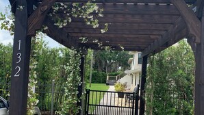 A wooden pergola with a brick pathway leading to a gated entrance. - Serenity By The River beach 🏖️ gateway  (Edgewater)