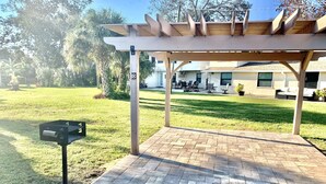 A covered patio area with a brick floor, a mailbox, and a pergola structure. - Serenity By The River beach 🏖️ gateway  (Edgewater)