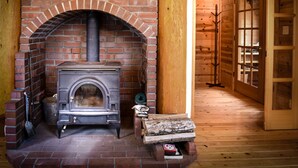 Un interior rústico de madera con chimenea de ladrillo, una puerta de madera con paneles de vidrio y piso de madera.