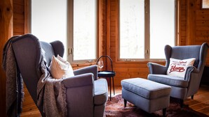 Una habitación acogedora con dos sillones grises, una mesita con un vaso y una alfombra de piel.