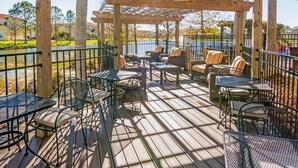 A wooden deck with outdoor seating, including tables and chairs, under a pergola.