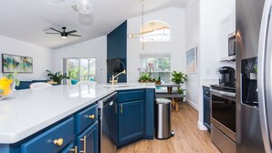 A modern kitchen with a central island, stainless steel appliances, and a ceiling fan.