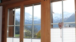 Una habitación con paredes de madera y ventanas amplias con vistas a un paisaje montañoso.