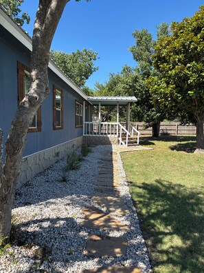 Ein Haus mit einer Veranda, einem gepflasterten Weg und einem umzäunten Garten.