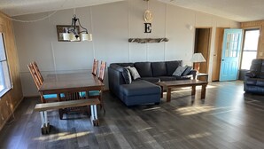 Un salon spacieux avec une table à manger en bois, un canapé bleu et une table basse.
