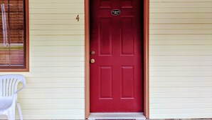 A red door with a brass doorknob and a small sign above it.