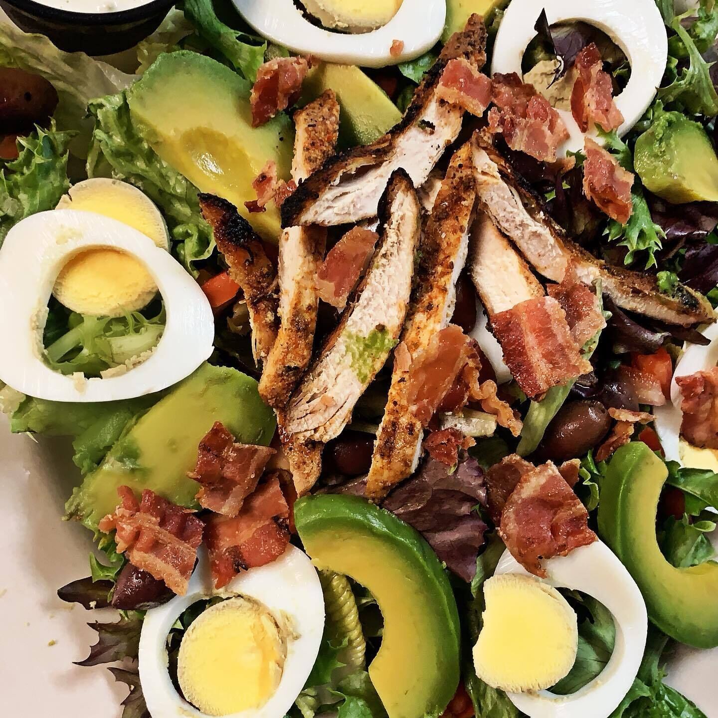 Ensalada con pollo, tocino, aguacate y huevos duros.