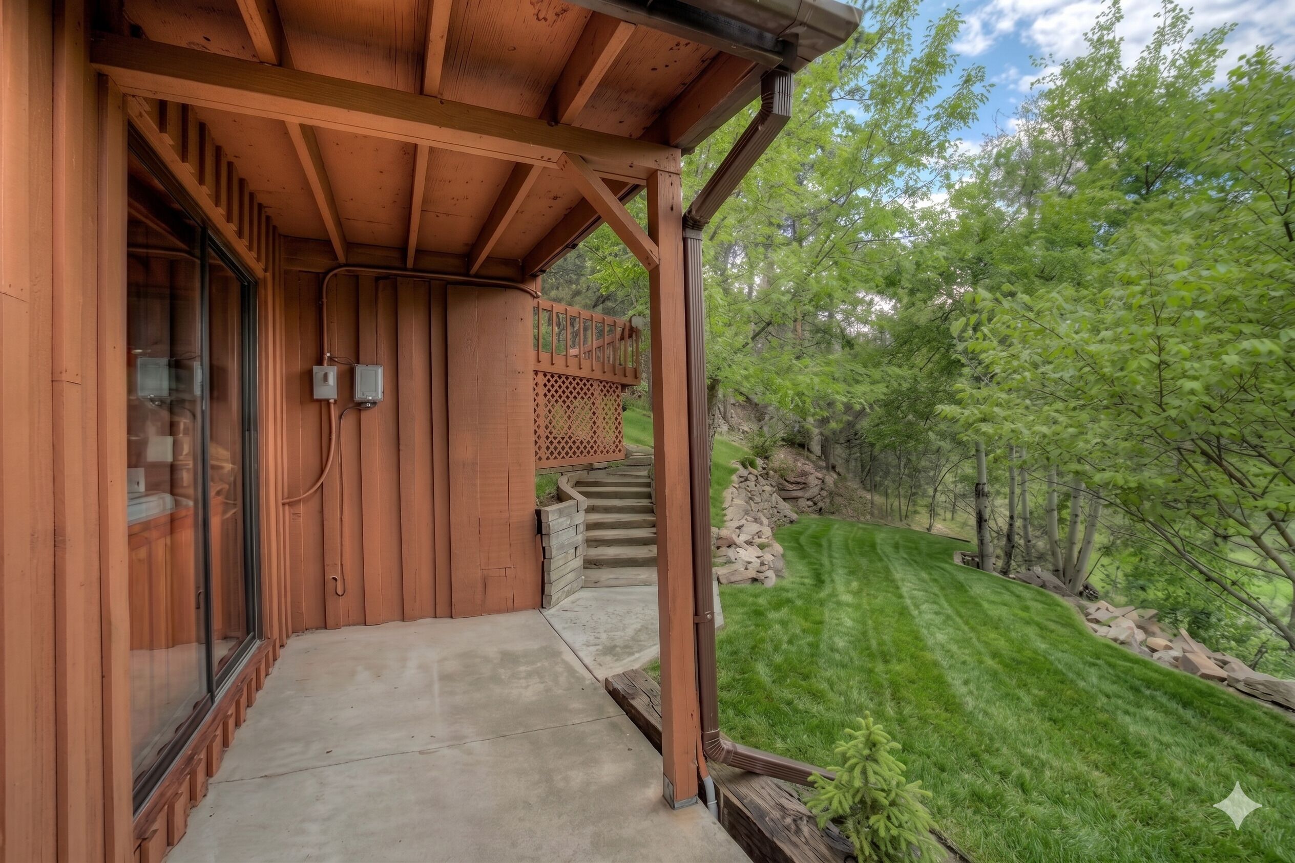 A wooden building with a covered porch, a concrete pathway, and a well-maintained lawn.