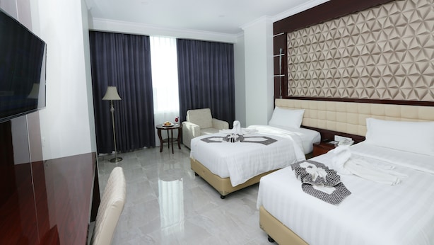 A hotel room with two beds, a TV, a desk, and a chair. - Sindoro Hotel Cilacap by Conary (Cilacap)