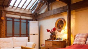 Um quarto acolhedor com cama, um sofá, uma mesa de madeira com uma bandeja de objetos, um espelho e uma janela com vidro jateado.
