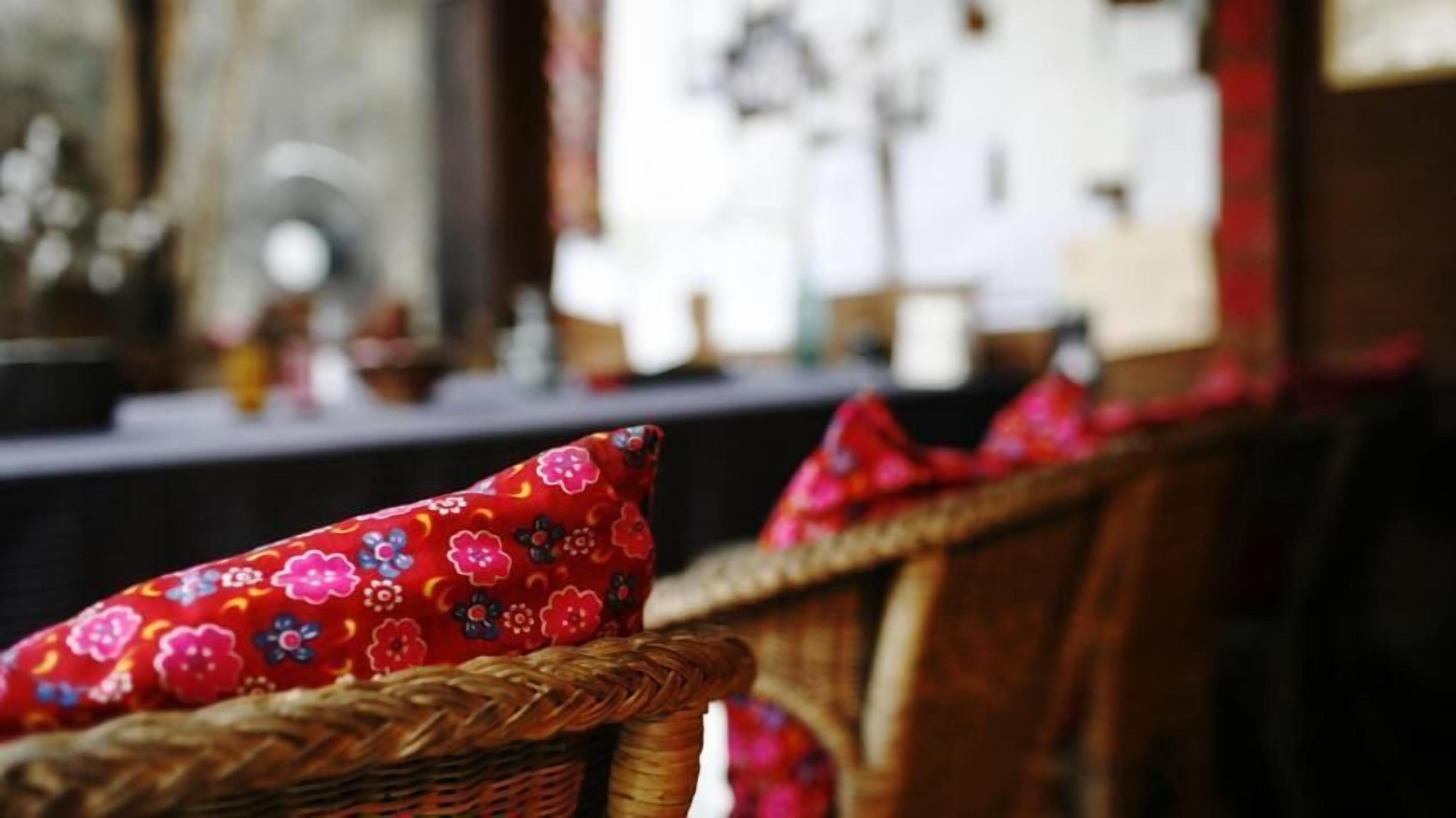 Wicker chairs with red floral cushions.