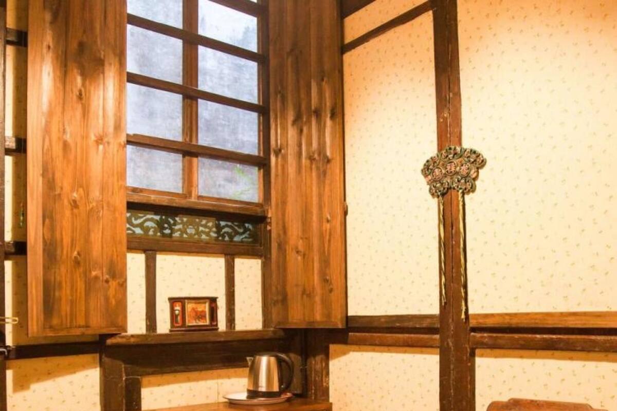 Une pièce de style traditionnel avec des murs en bois, une grande fenêtre, un meuble en bois doté de tiroirs, une chaise et un lampadaire.