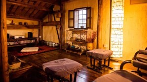 Quarto rústico com vigas de madeira, um tradicional candeeiro japonês e chão de tatame.