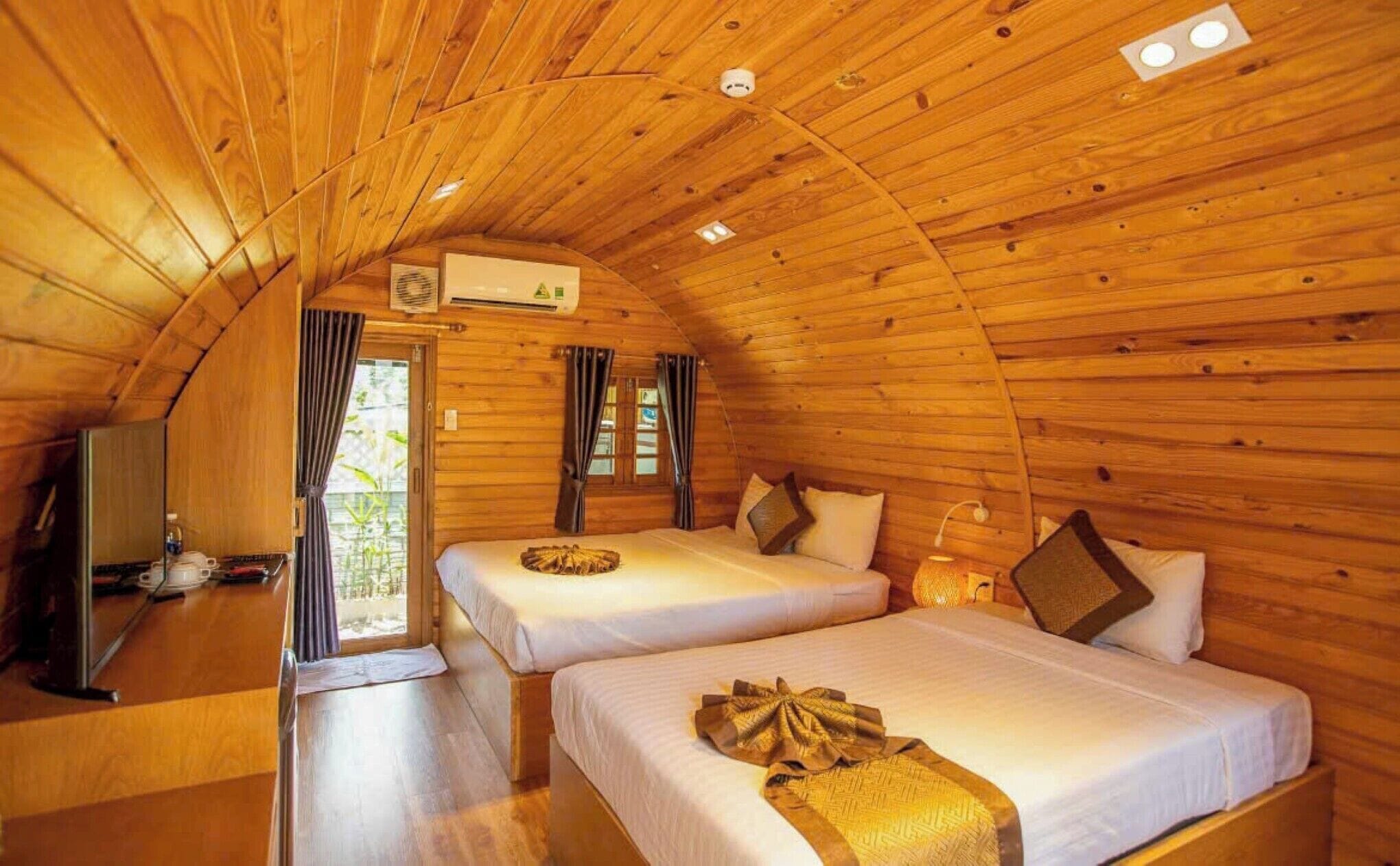 A cozy cabin with two beds, wooden walls, and a small kitchenette.