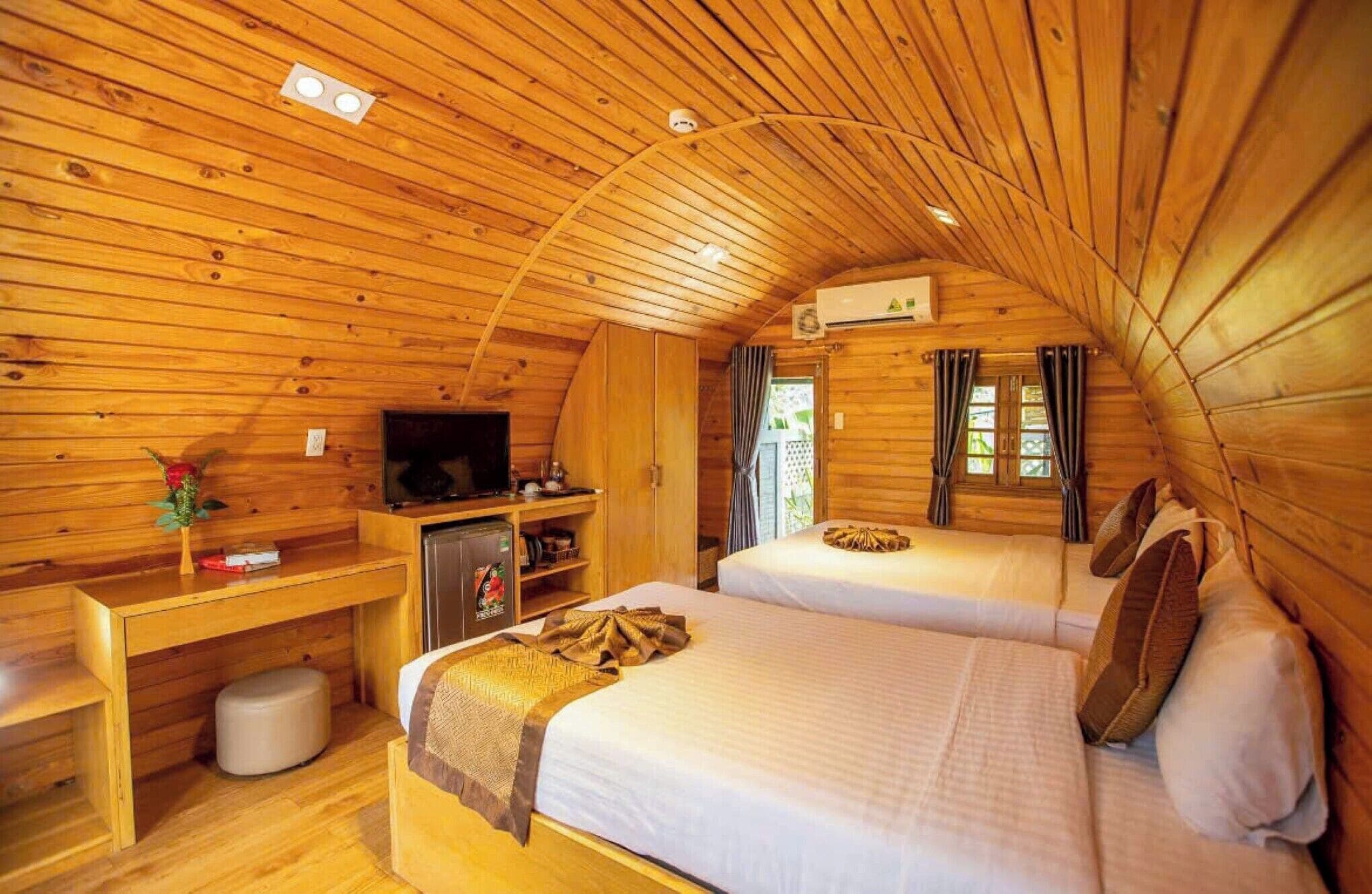 Una cabaña de madera acogedora con dos camas, un televisor y una pequeña kitchenette.
