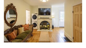 Una sala de estar con chimenea, un sofá, un espejo y un televisor.