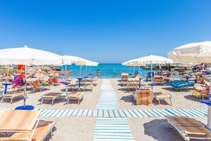 A beach with rows of sun loungers and umbrellas, a clear blue sky, and the ocean in the background. - Garden - 2 terraces - parking space - 100 m sea - wifi - Dishwasher (Carovigno)
