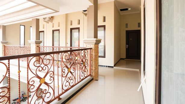 A spacious corridor with a decorative wrought iron railing, large windows, and a clean, modern interior design. - OYO Living 1743 Anie Residence (Surabaya)