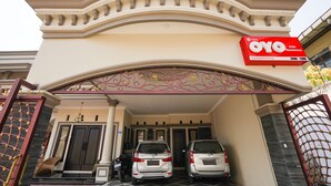 A modern building with a prominent red sign for OYO Antea Residence, featuring two parked cars and a decorative entrance arch. - OYO Living 1743 Anie Residence (Surabaya)