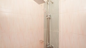 A shower with a handheld showerhead and a wall-mounted control panel. - OYO Living 1743 Anie Residence (Surabaya)