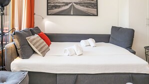 A neatly made bed with pillows and towels, a framed picture of a road on the wall, and a window with curtains. - Rosablanche C32 by Interhome (Siviez-Nendaz)