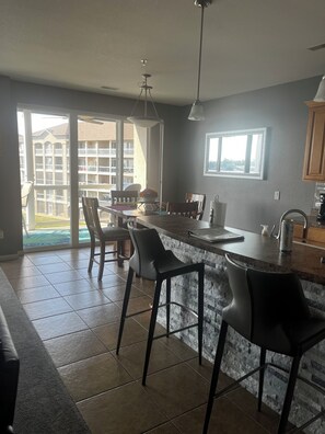 Cocina moderna con una isla grande, taburetes de bar y un comedor con sillas.