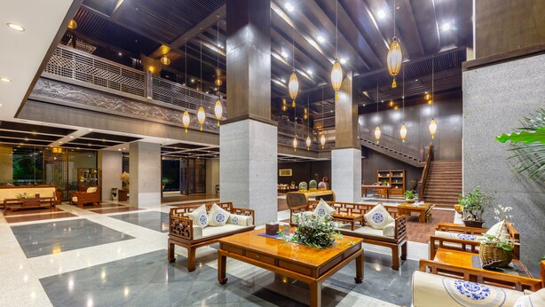 Eine geräumige Lobby mit hohen Decken, Holzmöbeln und hängenden Laternen.