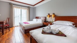 Ein Hotelzimmer mit zwei Betten, Holzböden, einem Schreibtisch und einem Stuhl.